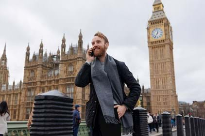 Young man taking work call in front of big ben in London England