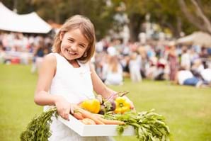 young girl holding basket of fresh food from farmers market