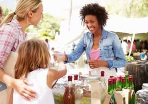 woman selling drinks at farmers market and getting to know customers